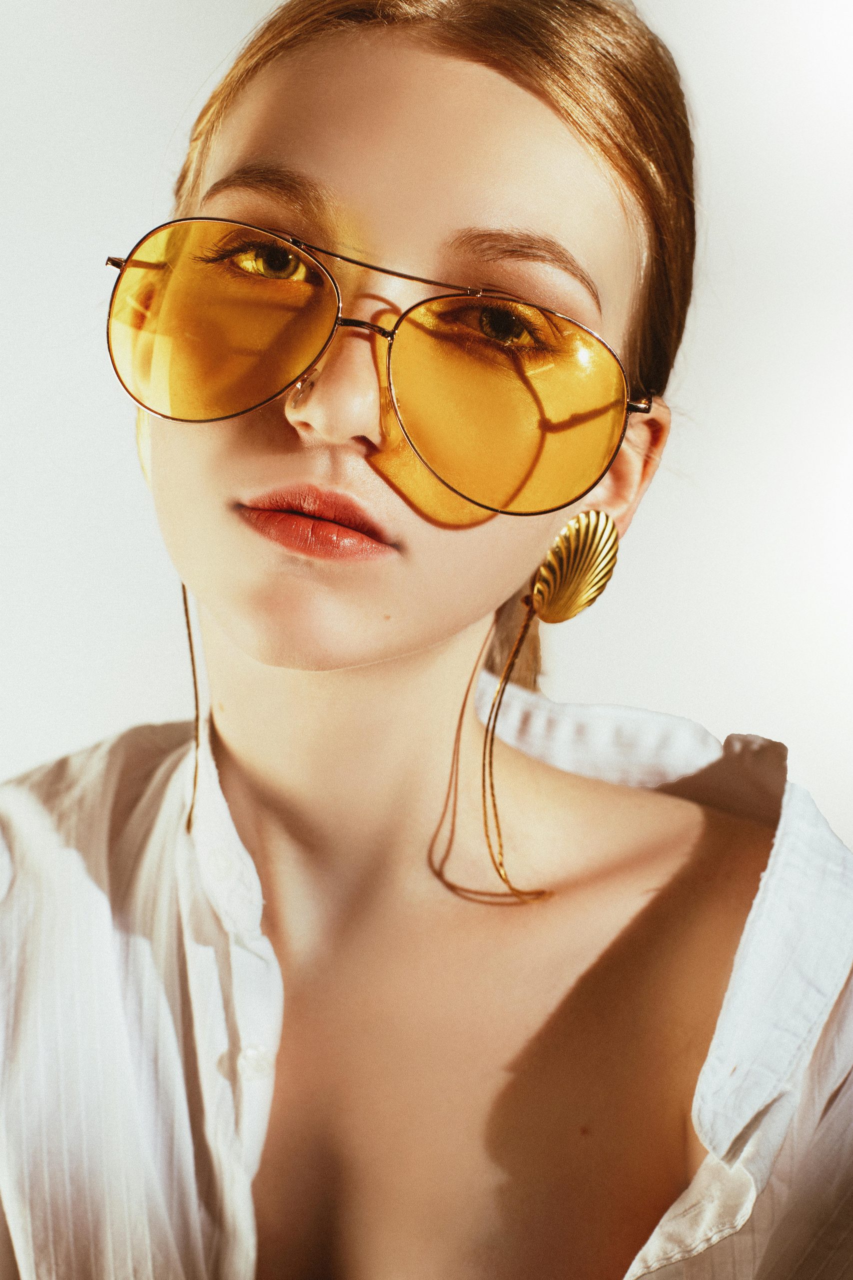 Chic portrait of a woman in yellow sunglasses and statement earrings.